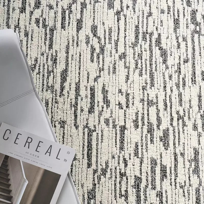 Close-up of a modern gray and white area rug with irregular line patterns, paired with a lifestyle magazine #Texture_Abstract Lines