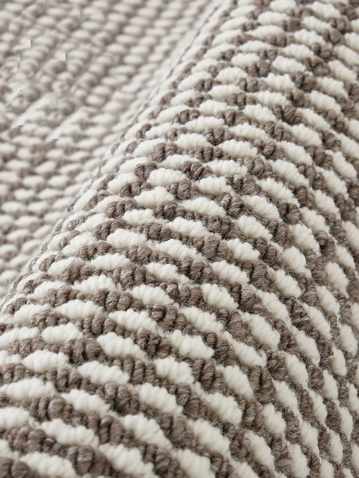 Close-up view of loop-textured wool blend rug in cream and taupe shades