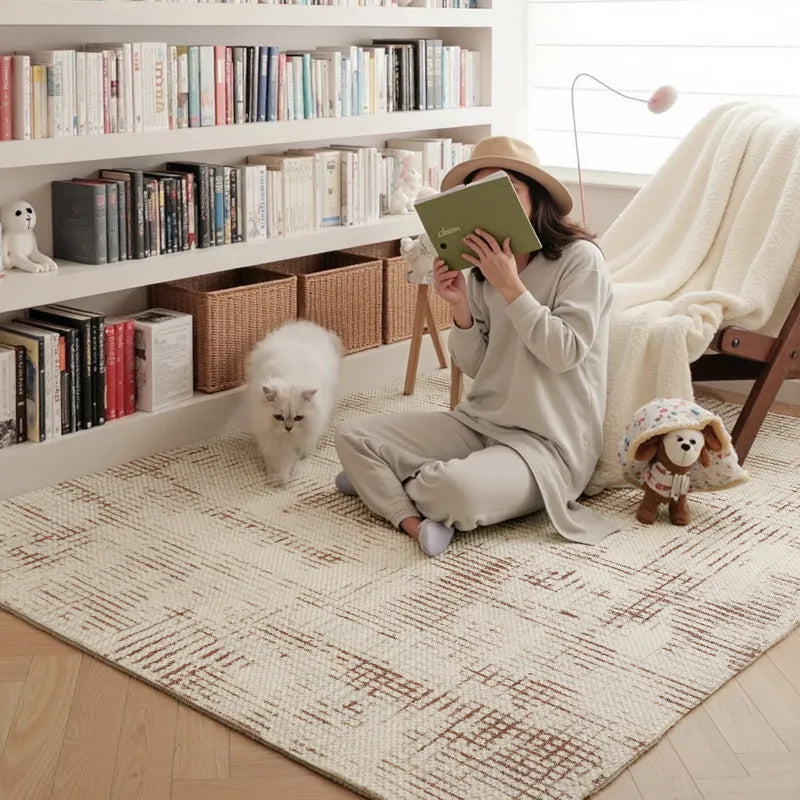 Cozy reading nook with a soft geometric patterned rug, white cat, floor bookshelf, and natural light streaming in
