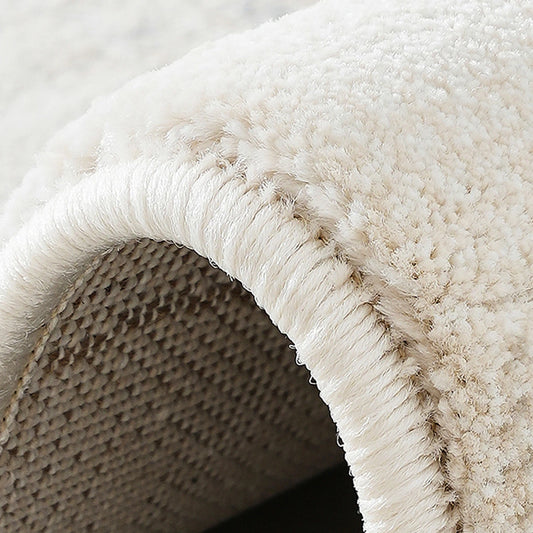 Close-up of reinforced edge binding on a cream abstract area rug