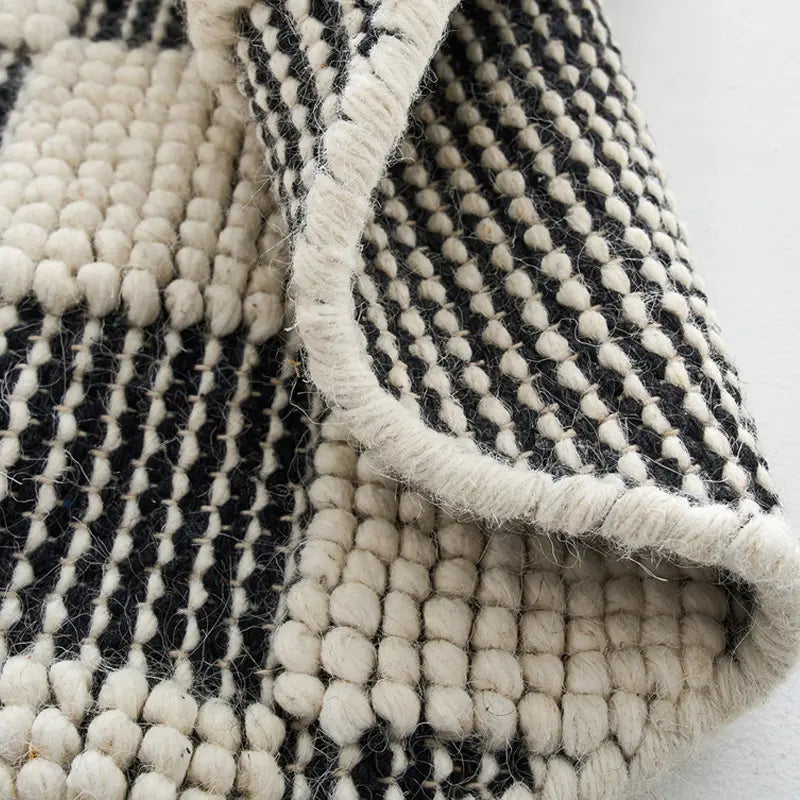 Close-up of the handwoven edge of a black and white checkered wool rug, showcasing its intricate craftsmanship and natural texture #color_Black & White Check