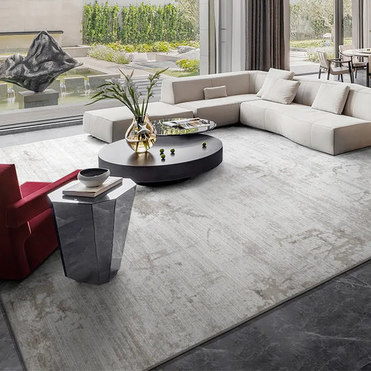 Modern luxury living room with an abstract rug, sectional sofa, and large windows overlooking a serene garden #color_gray