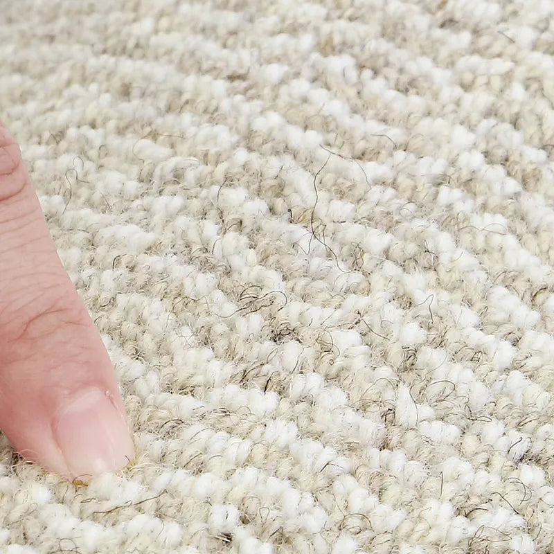 Finger pressing on textured wool carpet to showcase softness and density