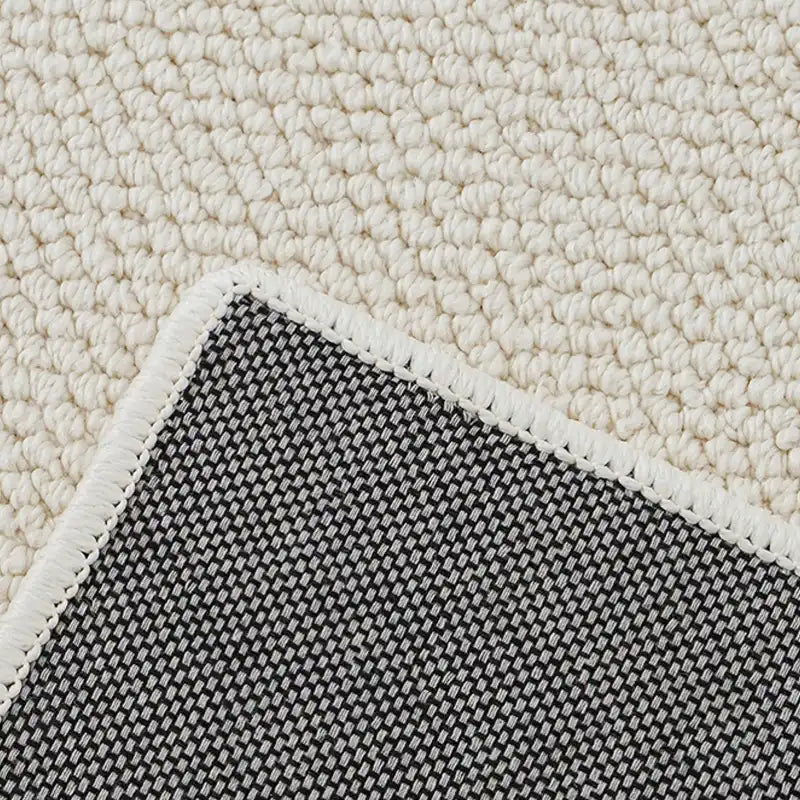 Detail of non-slip cotton backing on a natural wool rug with secure double-stitched edge