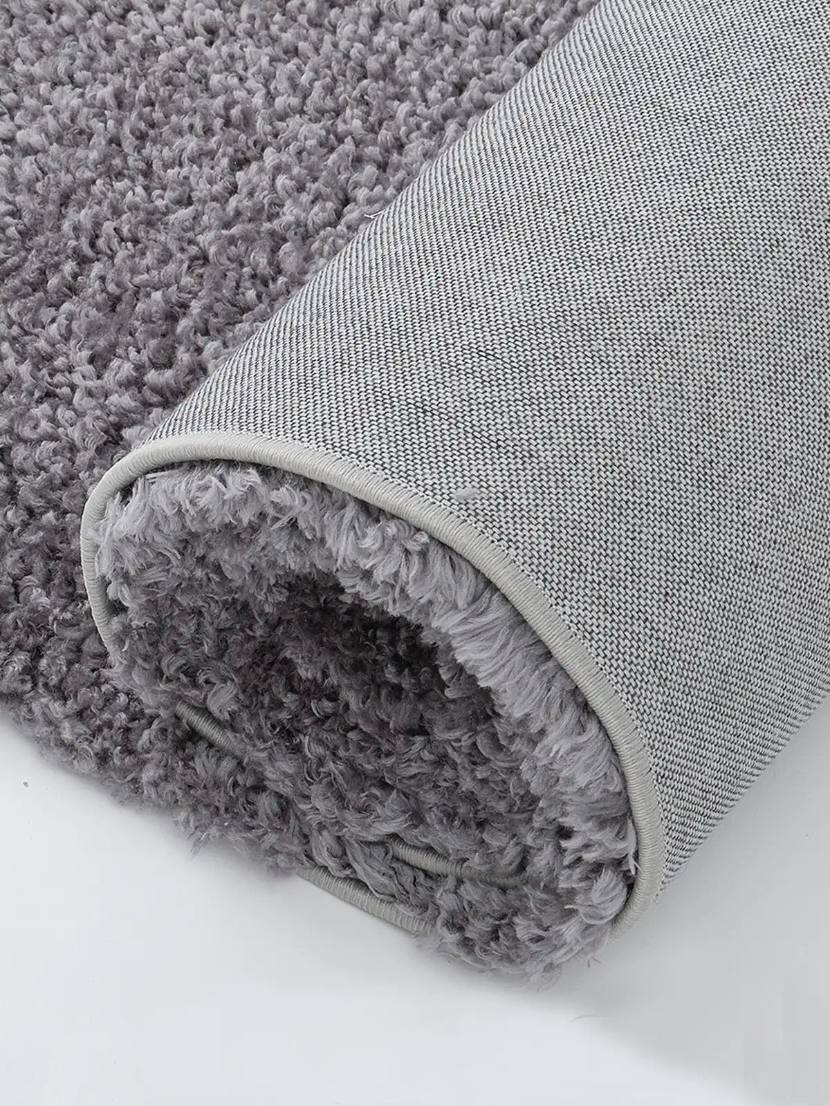 Close-up of the anti-slip backing on a light gray shaggy rug