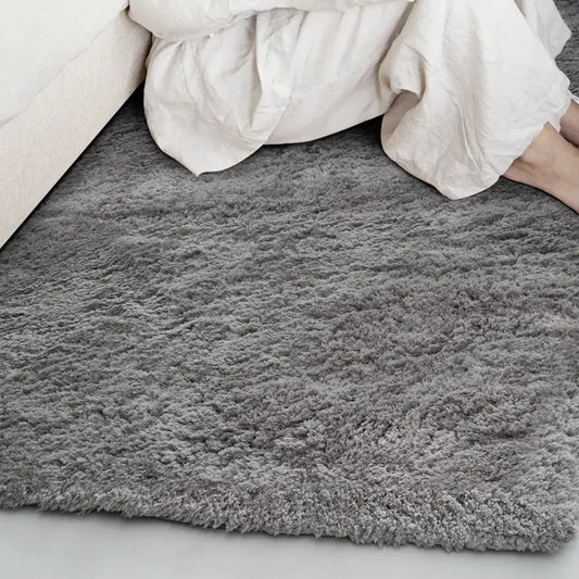 Soft gray shaggy rug placed next to a bed in a cozy bedroom #color_Charcoal Gray