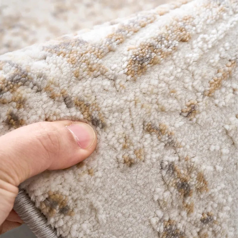 Hand holding a soft beige rug with detailed texture and earthy patterns