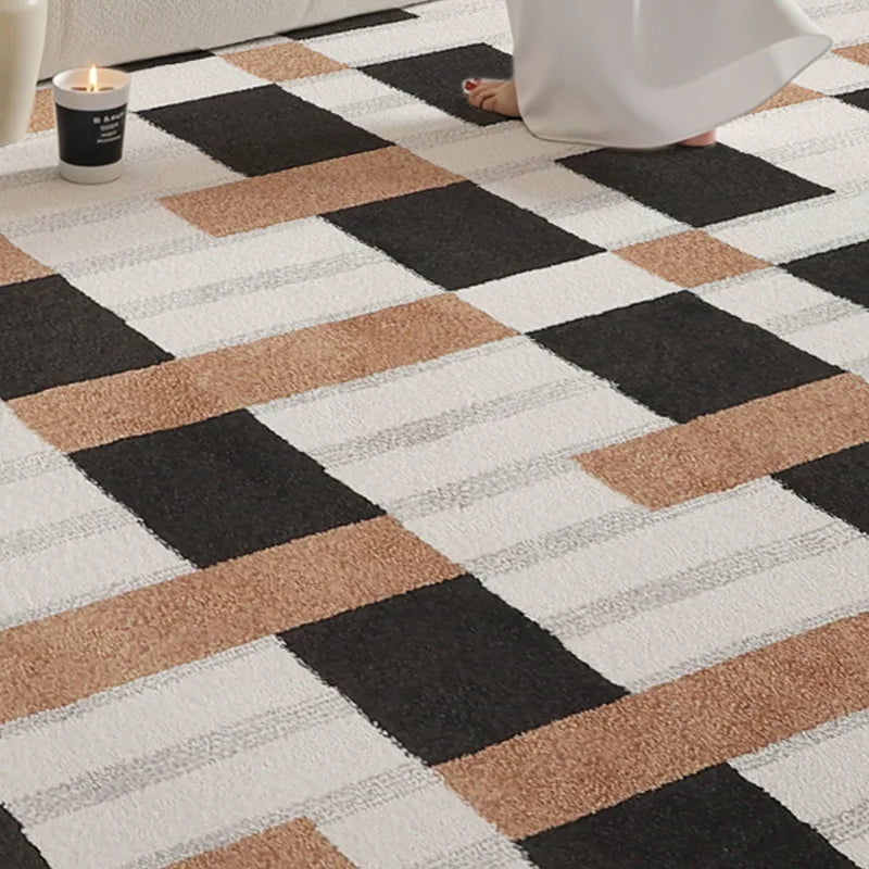 Close-up of soft woven rug with black, white, and brown geometric blocks under candlelight and bare feet