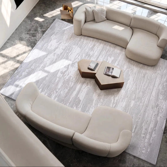 Textured gray rug in a modern living room with curved beige sofas and geometric coffee tables #Texture_Linear Drift