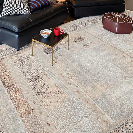 Close-up of a textured vintage area rug with geometric patterns in a modern living room with leather seating