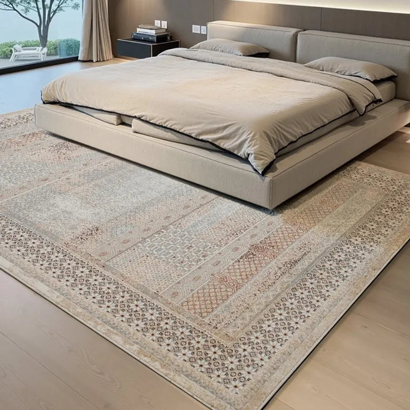 Vintage patchwork area rug in light neutral tones placed under a modern low-profile bed in a minimalist bedroom