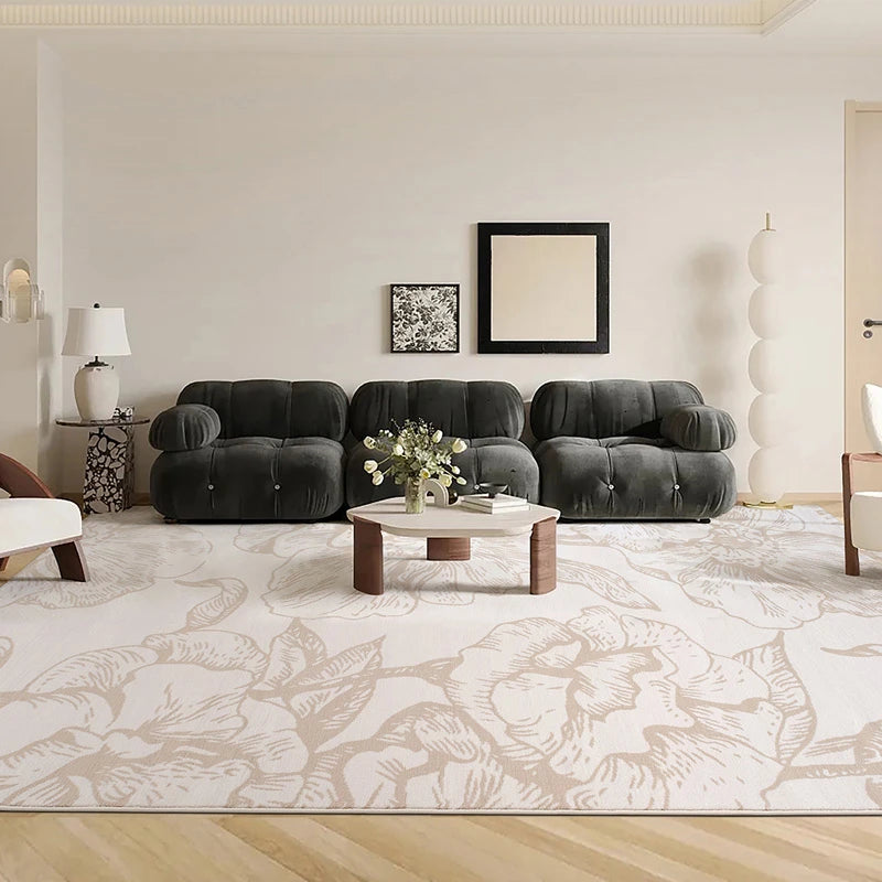 Beige floral rug in a modern living room with black tufted sofas and minimalist decor