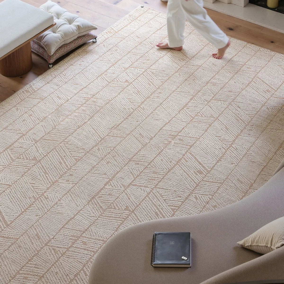 Overhead view of a beige geometric leaf rug with a structured woven texture and warm neutral pattern