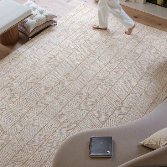 Overhead view of a beige geometric leaf rug with a structured woven texture and warm neutral pattern