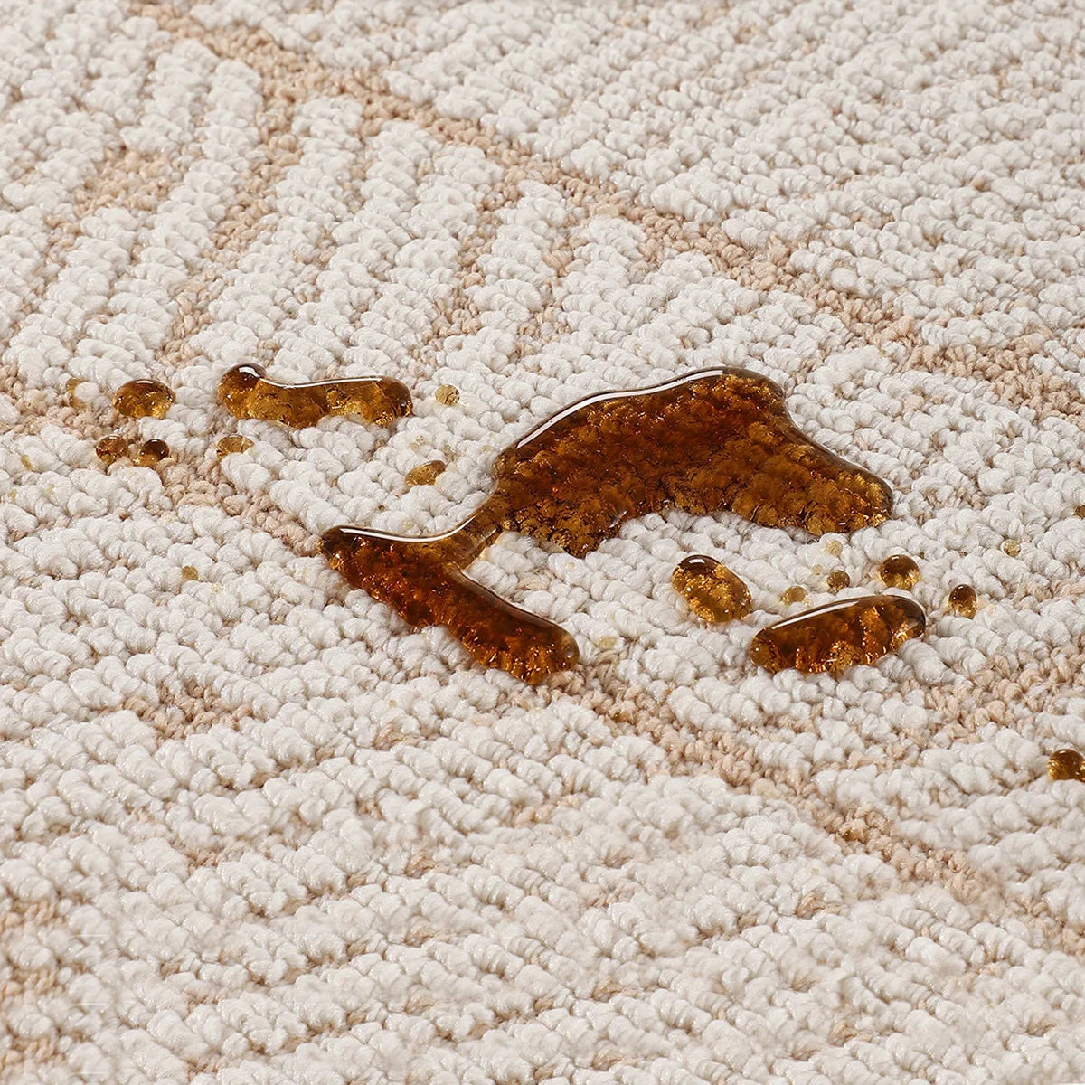 Beige geometric leaf rug with a dense woven surface shown with liquid spill detail