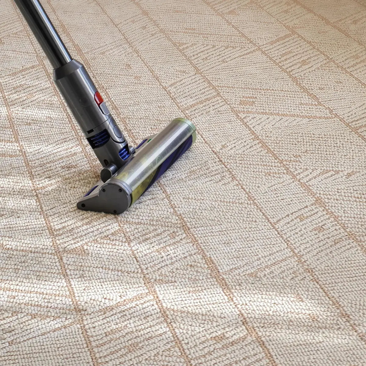 Vacuum cleaning a beige geometric leaf rug with a structured loop texture and woven surface