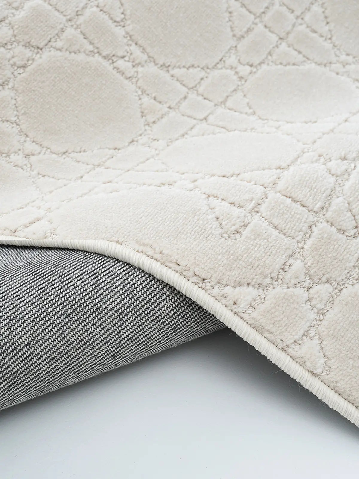 Close-up of the beige rug’s backing with durable stitching and intersecting patterns, highlighting its high-quality craftsmanship and sturdy construction