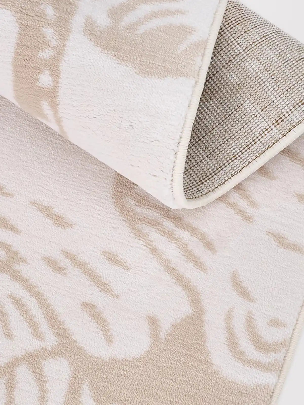 A close-up view of a beige rug with a durable non-slip backing and fine stitched edges, emphasizing quality and safety