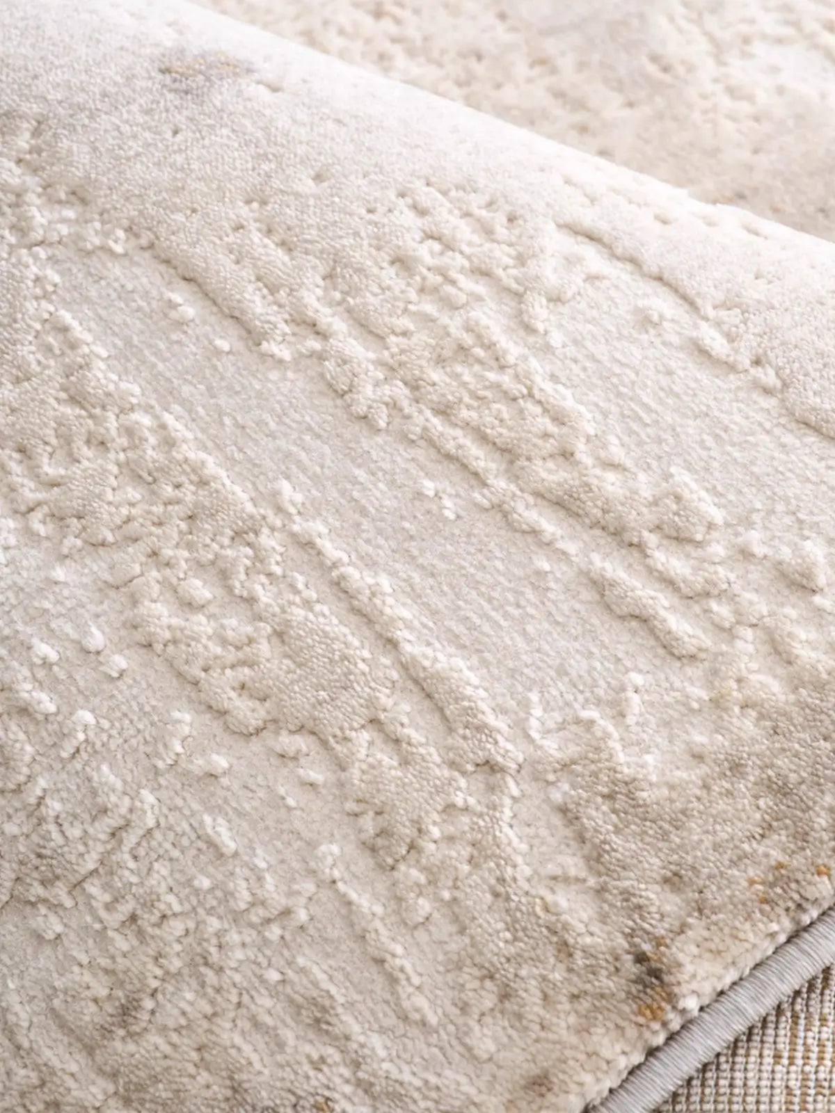 Close-up view of a beige textured rug showing its soft surface and intricate detailing