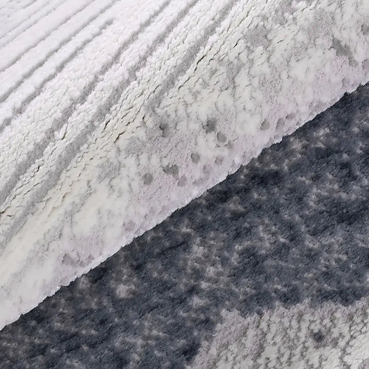Blue-gray abstract area rug folded texture detail showing soft raised pile and layered gray blue pattern.