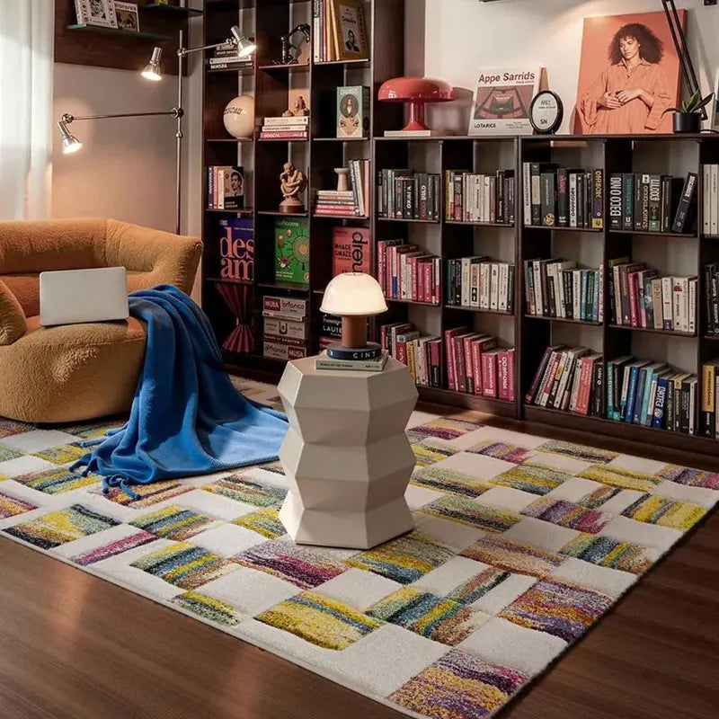 Colorful geometric patchwork rug in a cozy reading nook with an orange armchair, blue blanket, and bookshelves