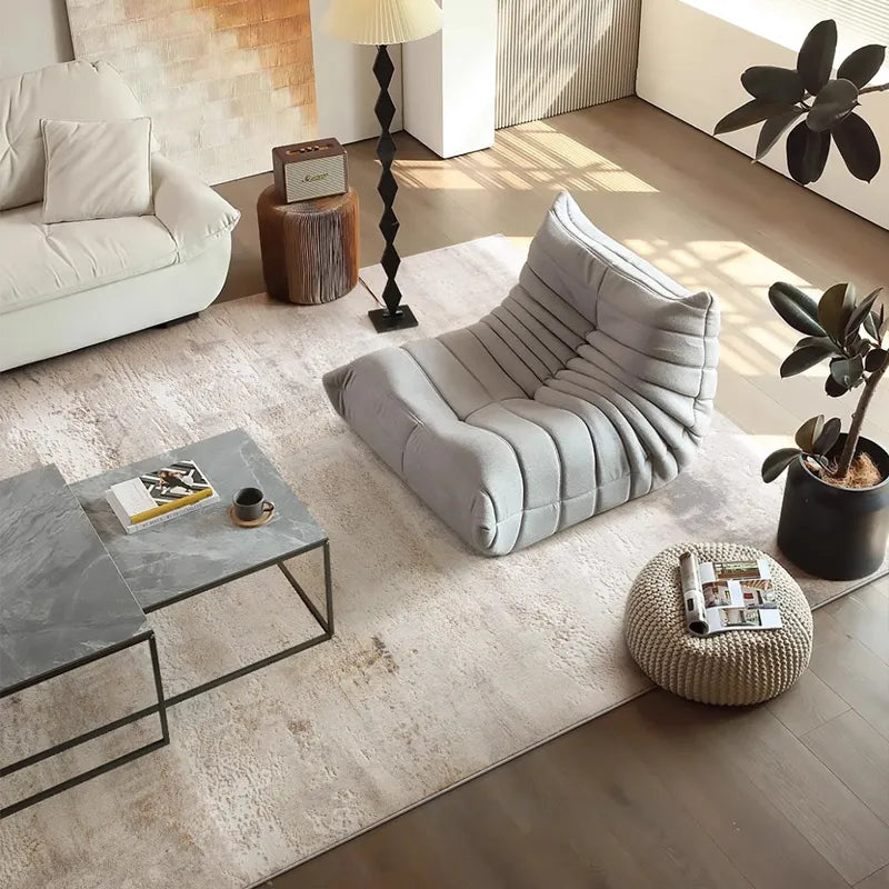 Neutral-tone rug in a modern living room with gray sofa, marble table, and natural light
