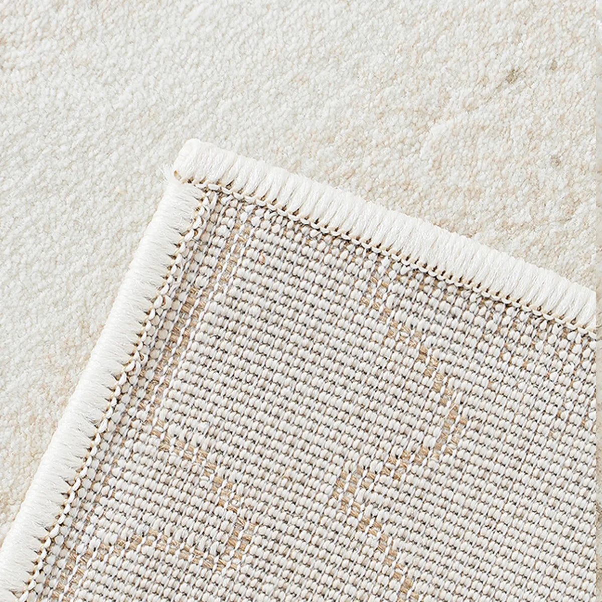 Back view of cream abstract area rug showing durable woven backing and edge finish