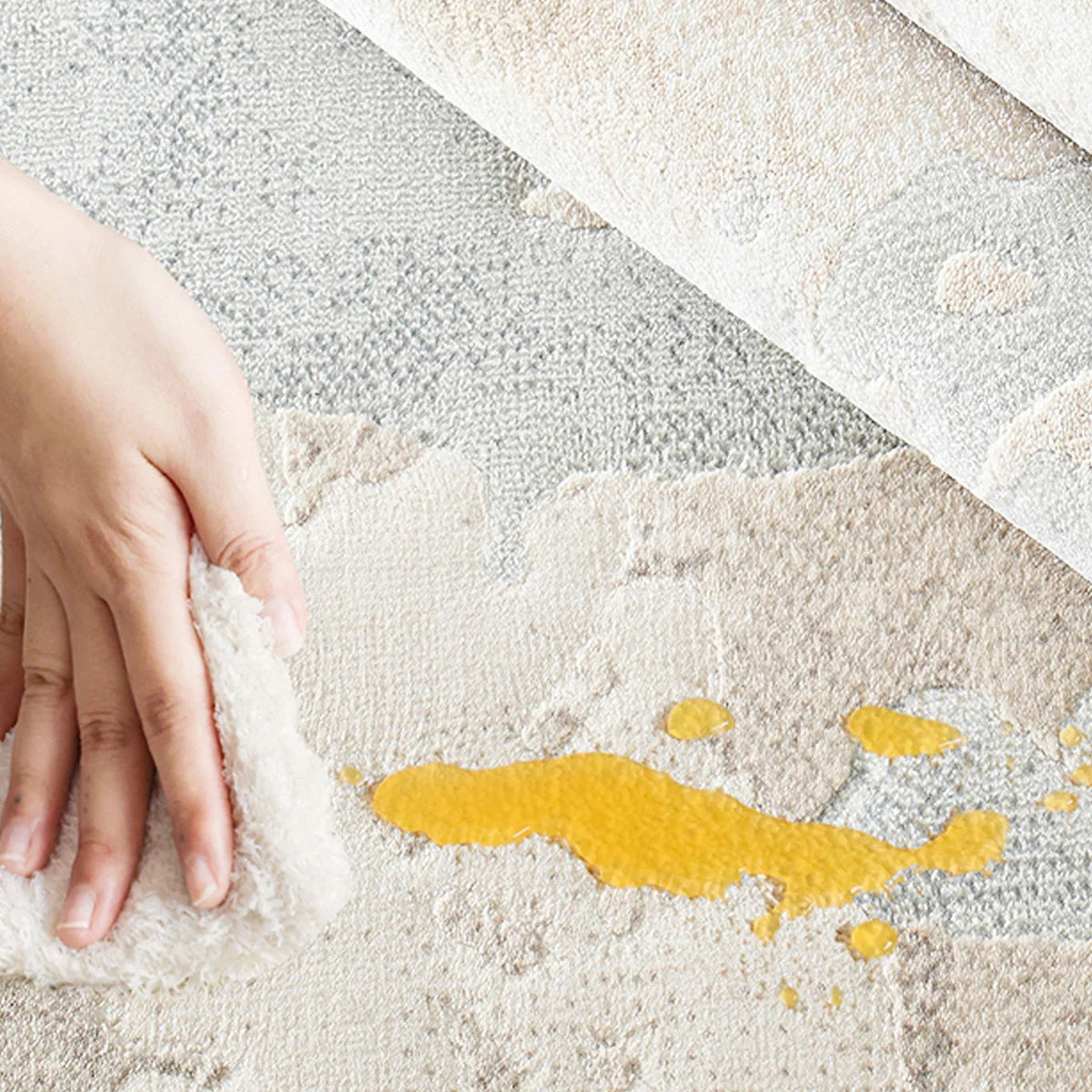Cream abstract area rug with stain-resistant surface being cleaned after a liquid spill