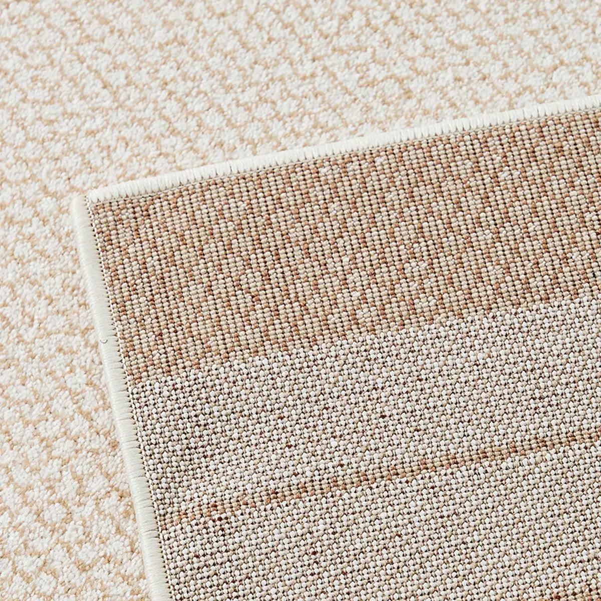 Close up of the woven backing and finished edge on a cream beige border rug