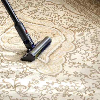 Vacuum cleaning a cream beige Persian area rug with a dense woven surface for easy everyday maintenance.