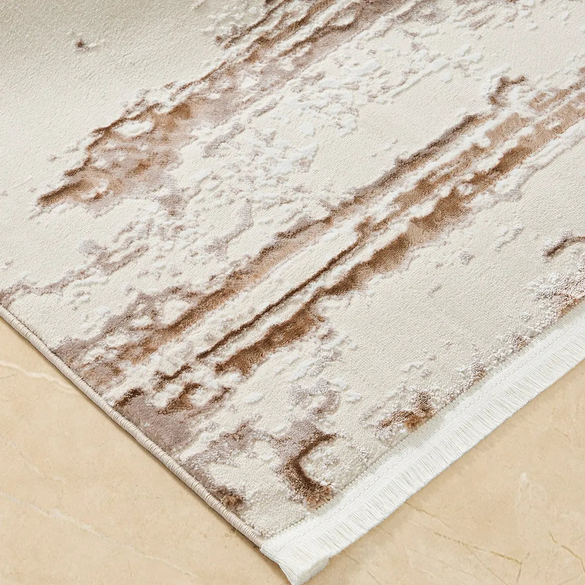 Close-up of cream brown distressed abstract area rug showing bound edge and textured surface