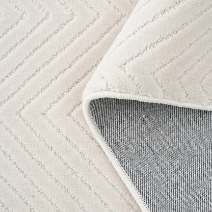 Cream geometric rug with folded corner showing woven backing and stitched edge detail