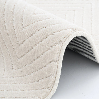 Cream geometric rug with folded edge showing soft textured surface and woven backing detail