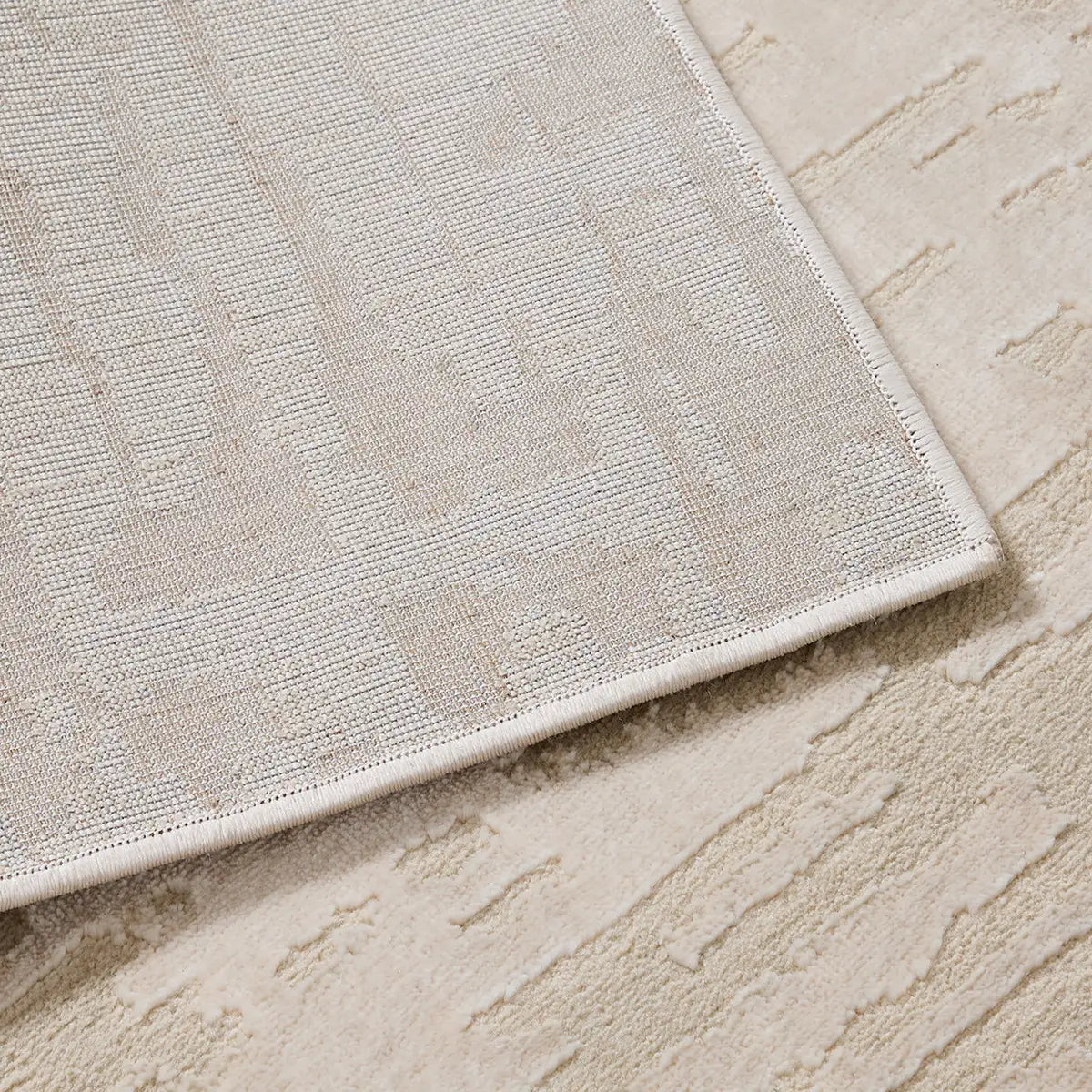 backing structure of cream area rug showing woven base and reinforced edges