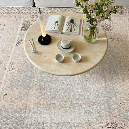 Cream vintage area rug with intricate geometric patterns under a floral coffee table setup in a cozy living room