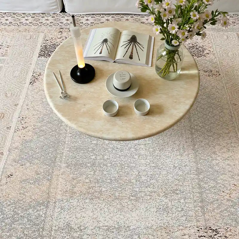 Cream vintage area rug with intricate geometric patterns under a floral coffee table setup in a cozy living room