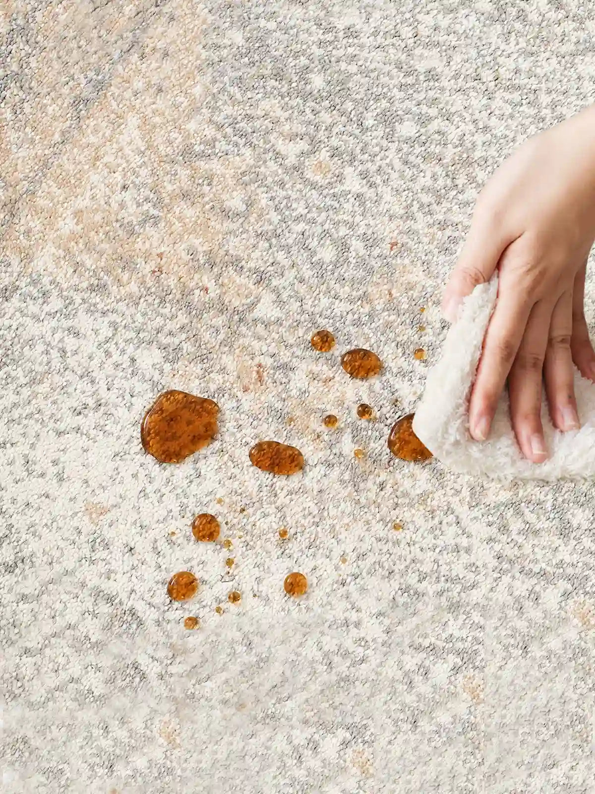 Close-up of coffee spill on vintage rug being wiped clean, showcasing its stain-resistant and easy-to-clean surface