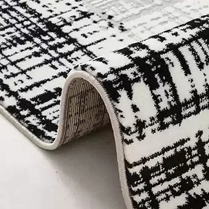 Detailed view of a modern black-and-white area rug with a textured pattern and durable folded edges for long-lasting quality 