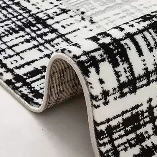Detailed view of a modern black-and-white area rug with a textured pattern and durable folded edges for long-lasting quality 