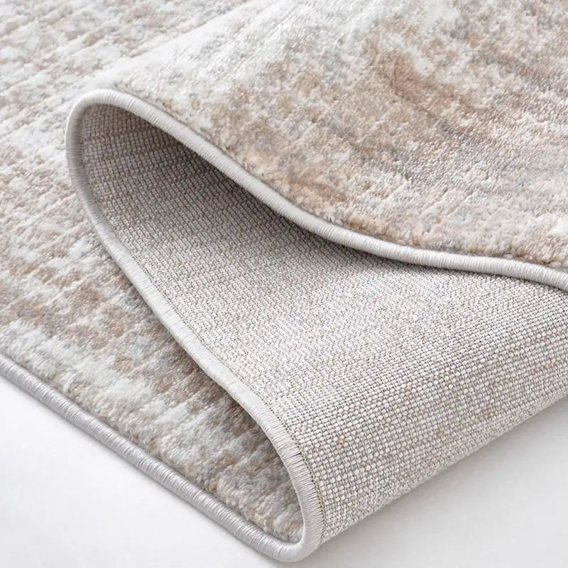 Close-up of the gray abstract rug's backing showing a non-slip jute material
