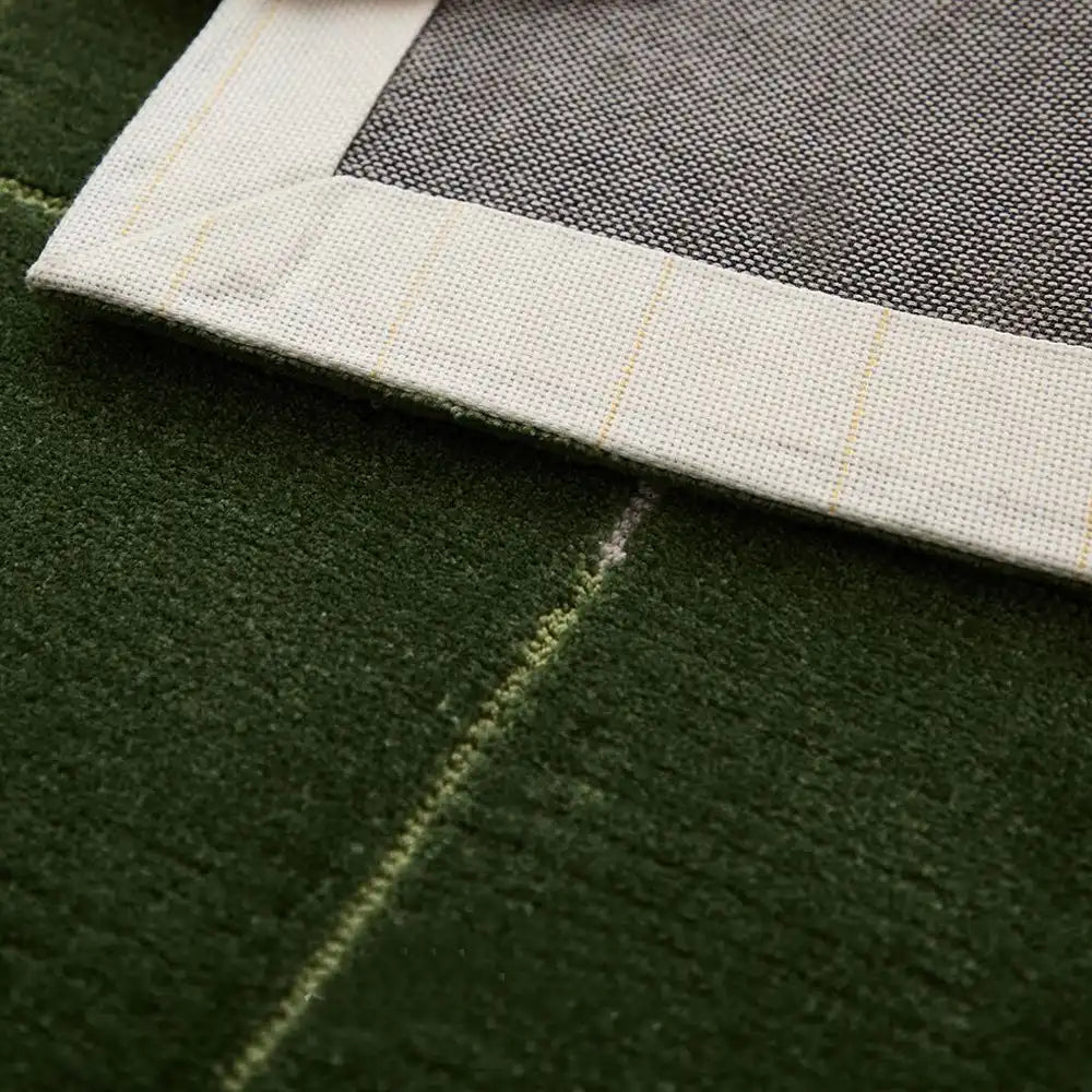 Close-up of bound edge stitching on a green grid rug for a clean finish.