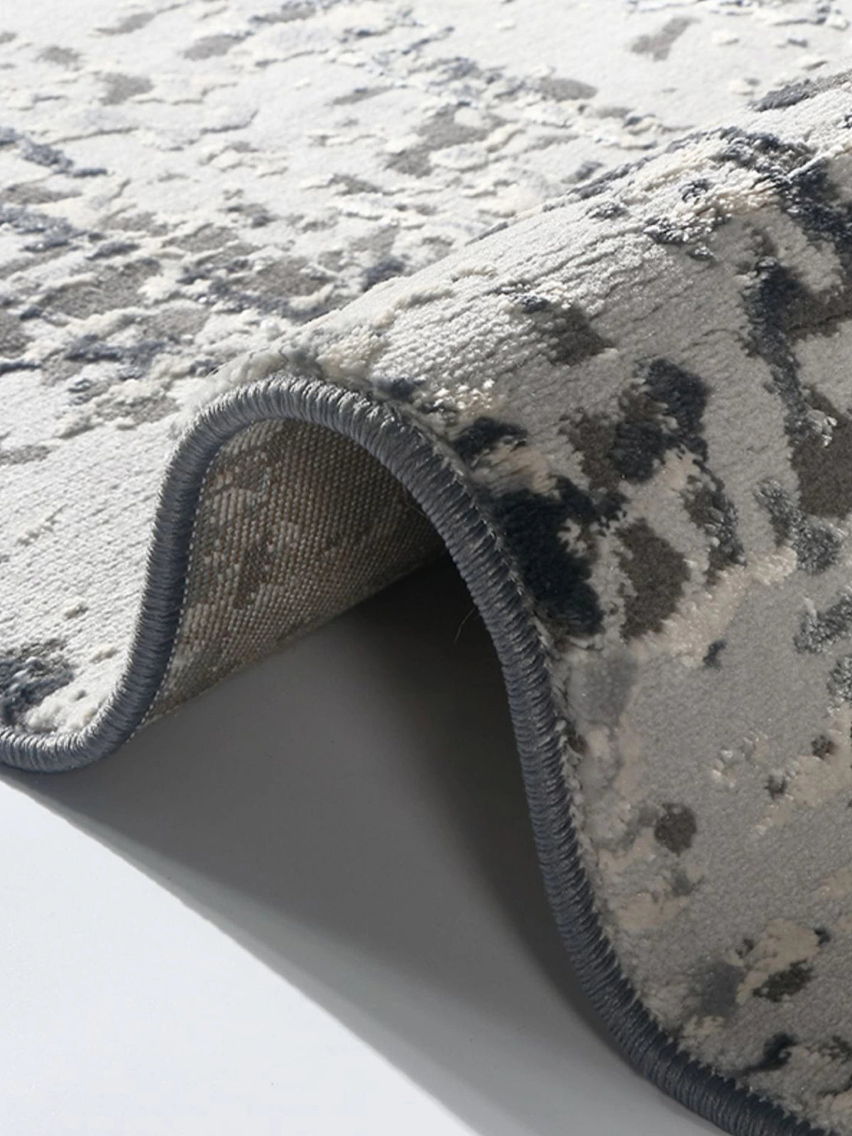 Folded grey abstract rug showing the neatly stitched edges and soft fabric texture