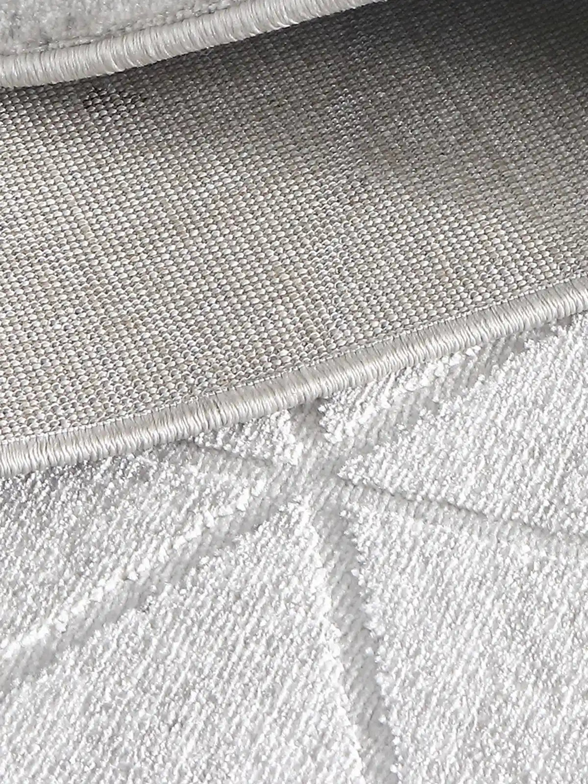 Close-up of grey geometric-patterned rug showcasing durable woven backing, reinforced stitched edge, and premium craftsmanship