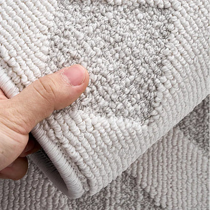 A hand holding a white rug to showcase its thick, soft texture and durable craftsmanship