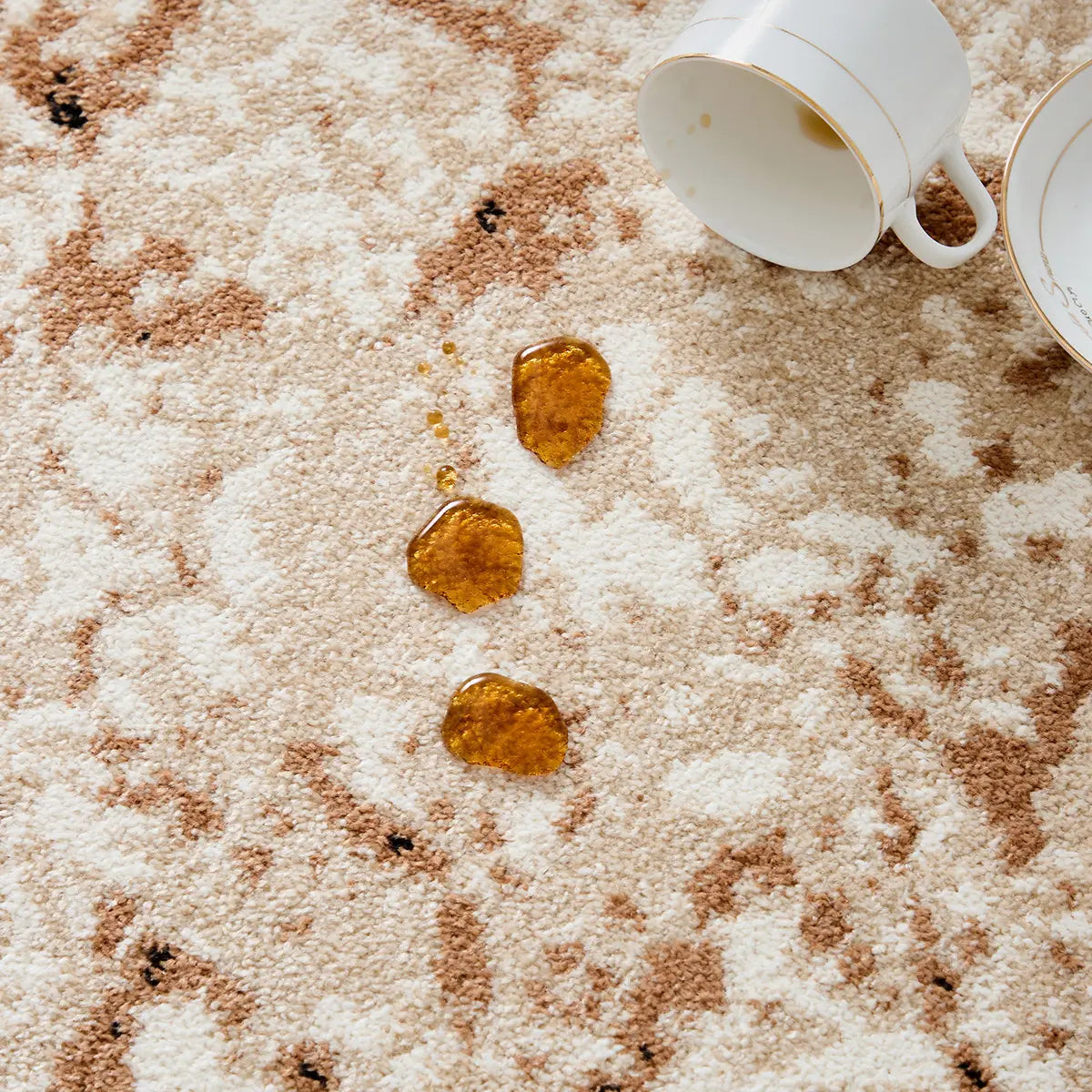 Ivory beige abstract area rug demonstrating spill-resistant surface with liquid remaining on top of the fibers