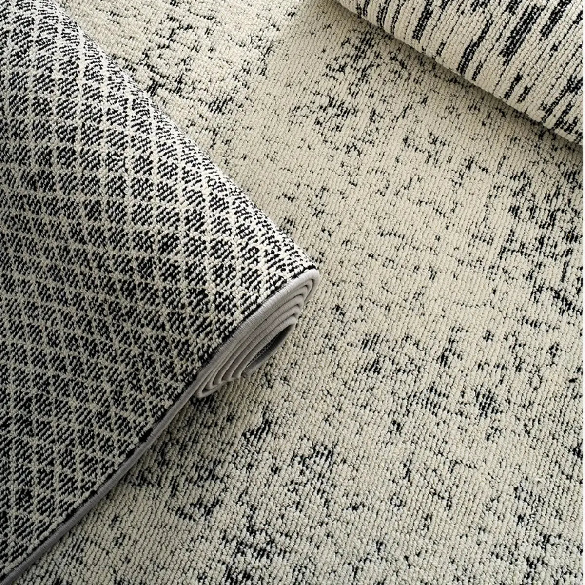 Folded ivory black textured area rug showing dense woven texture and structured modern construction