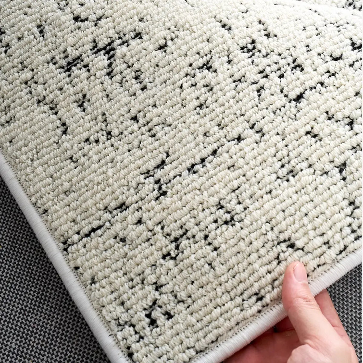Soft ivory black woven rug texture with subtle speckled detailing and comfortable dense surface