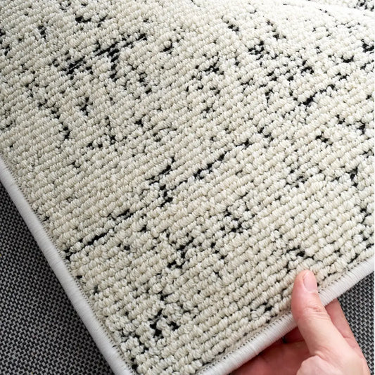 Soft ivory black woven rug texture with subtle speckled detailing and comfortable dense surface