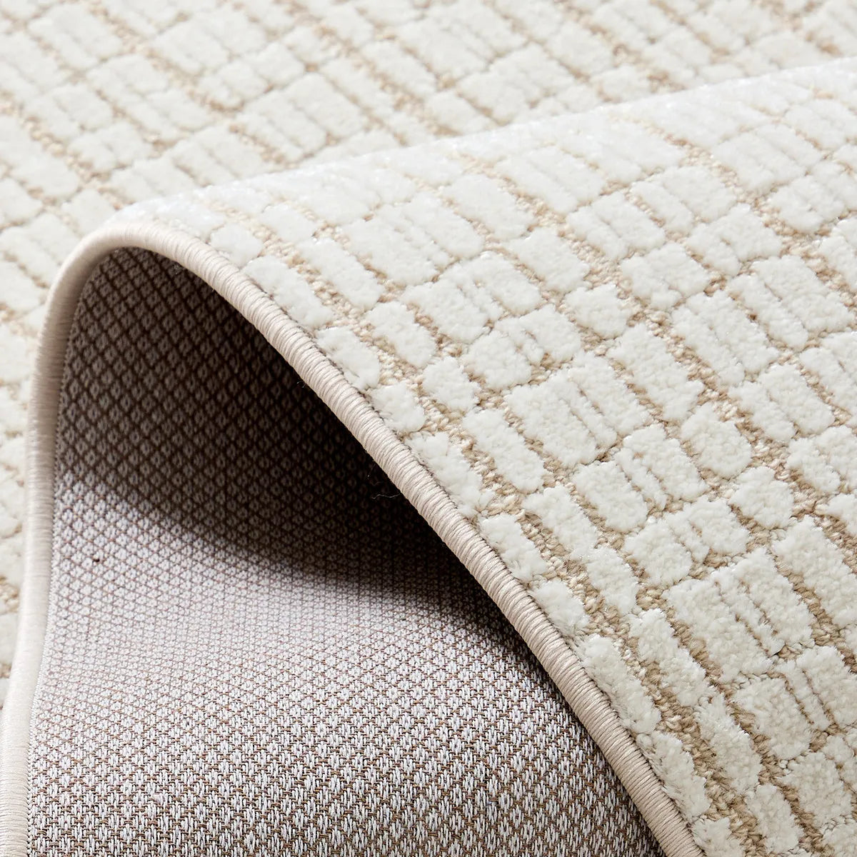 Ivory cut and loop grid area rug showing cotton backing and reinforced edge binding