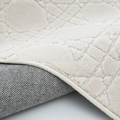 Ivory geometric area rug with bound edge and woven backing detail for a stable floor fit